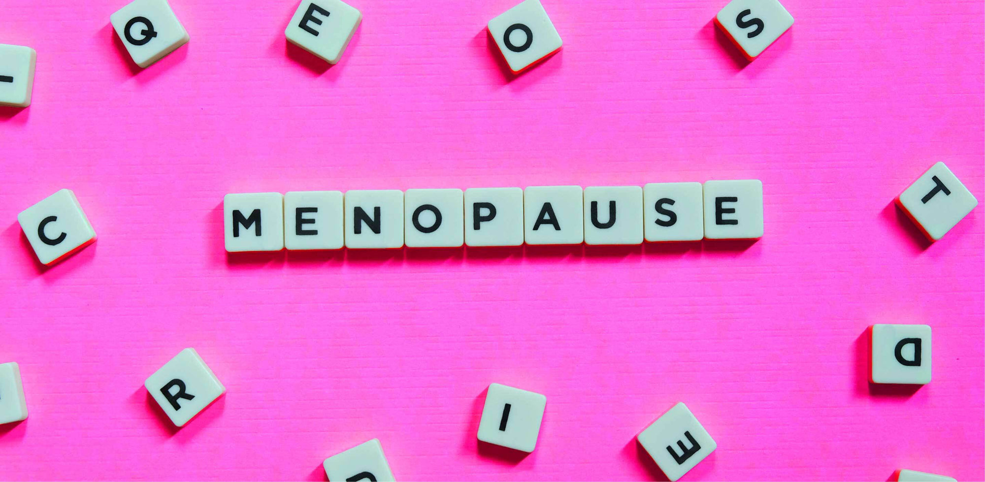 Word 'Menopause' spelled out with letter tiles on bright pink background, symbolizing women’s health and life transitions.
