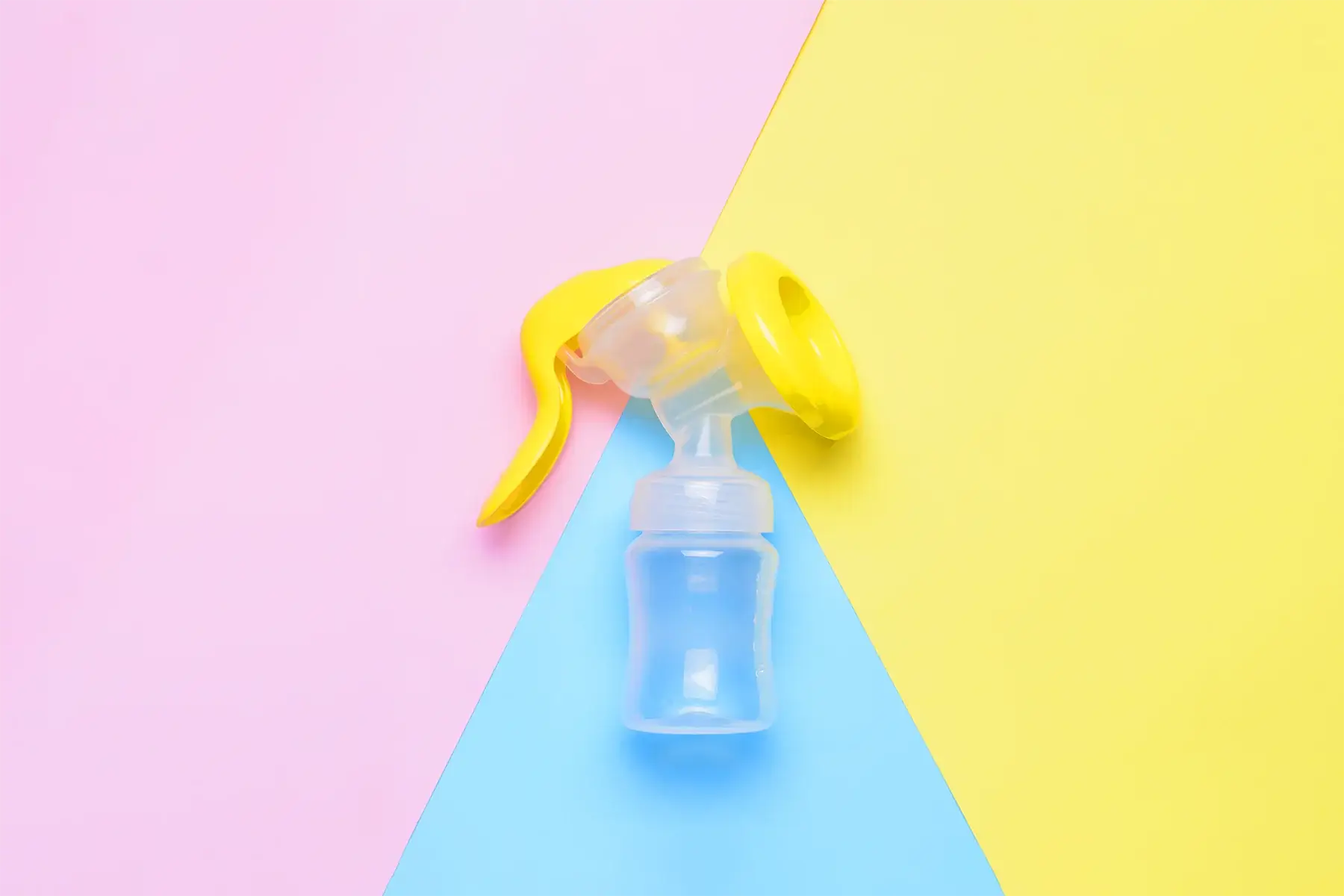 Manual breast pump with yellow handle on colorful pastel background for breastfeeding mothers.