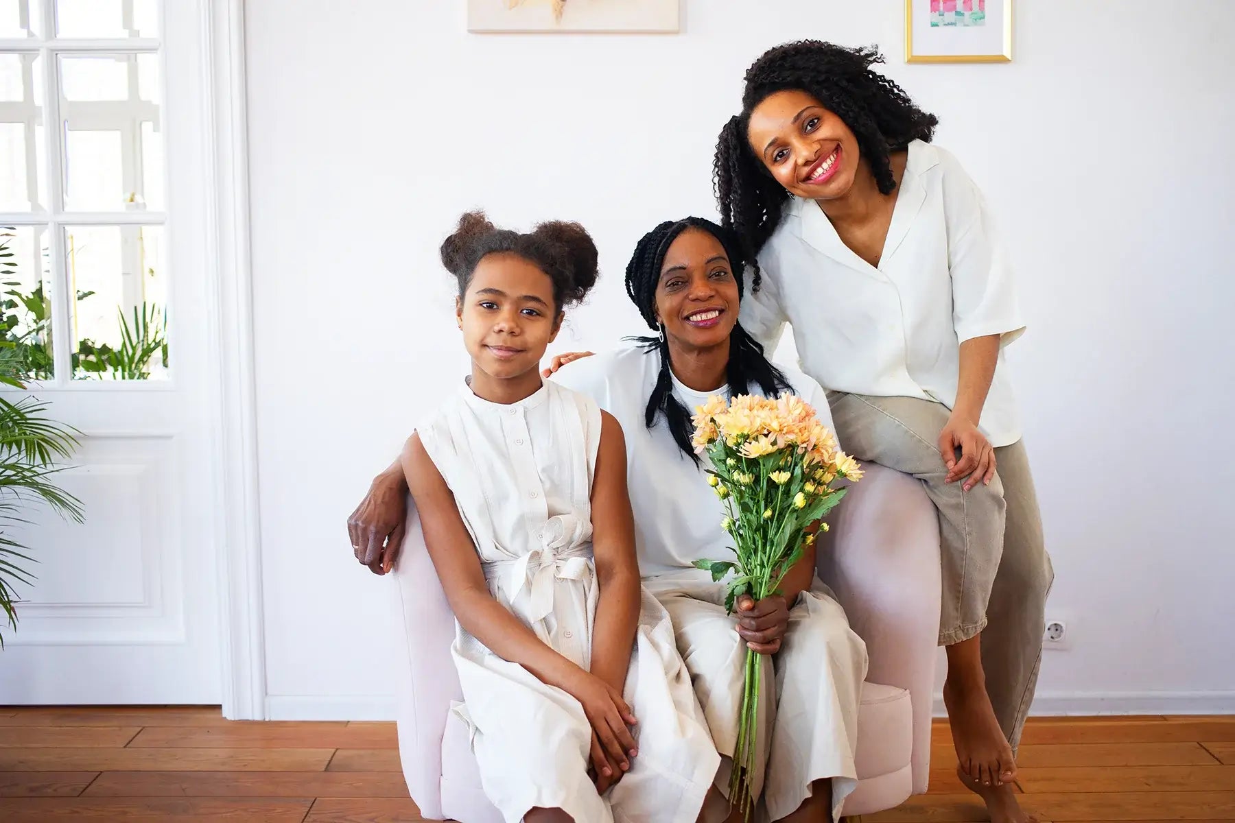 Three generations of women smiling together at home, symbolizing family love, support, and maternal bonds.