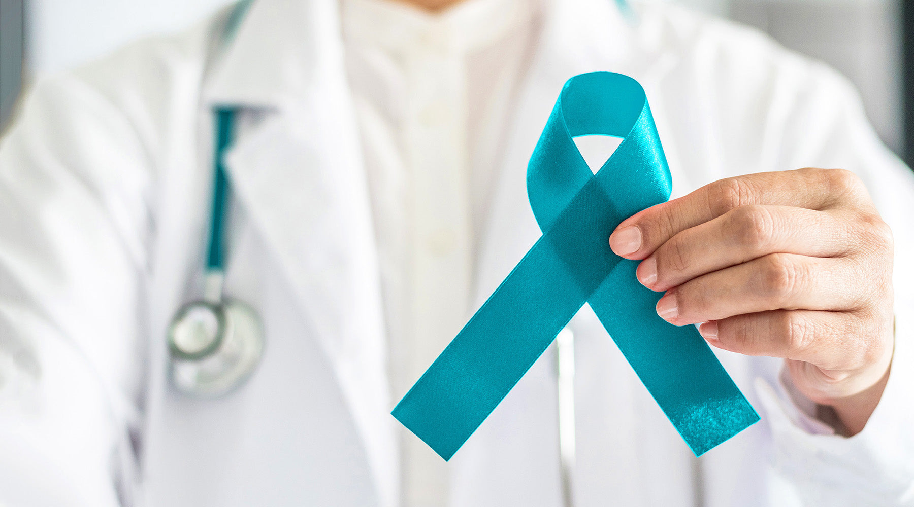 Doctor holding a teal awareness ribbon, symbolizing support for ovarian cancer awareness and women's health.