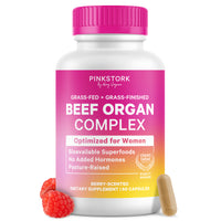 Pink Stork Beef Organ Complex dietary supplement bottle with a bright pink cap and a pink-to-yellow label, shown on a white background with two raspberries and one capsule.