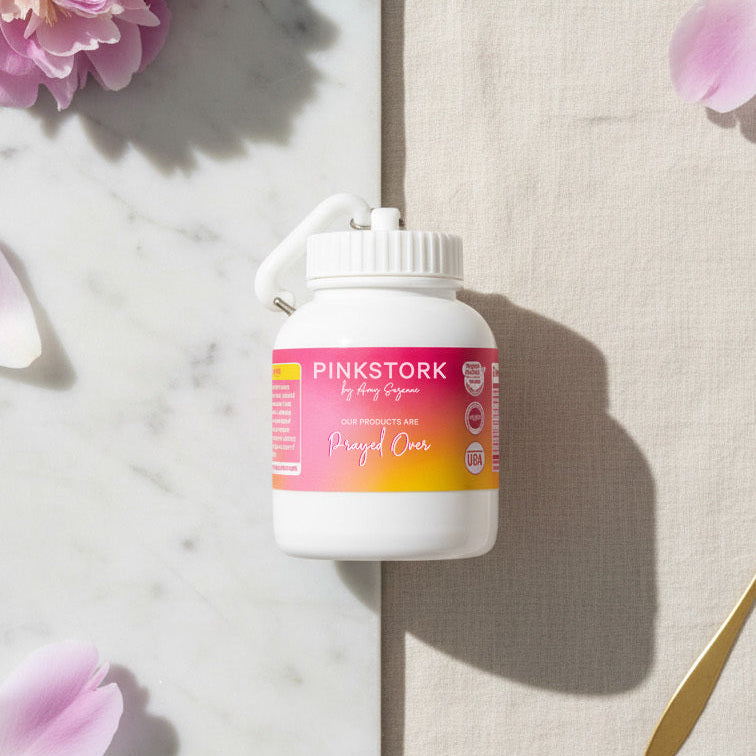 Pinkstork product bottle on a marble surface with pink flowers and petals.