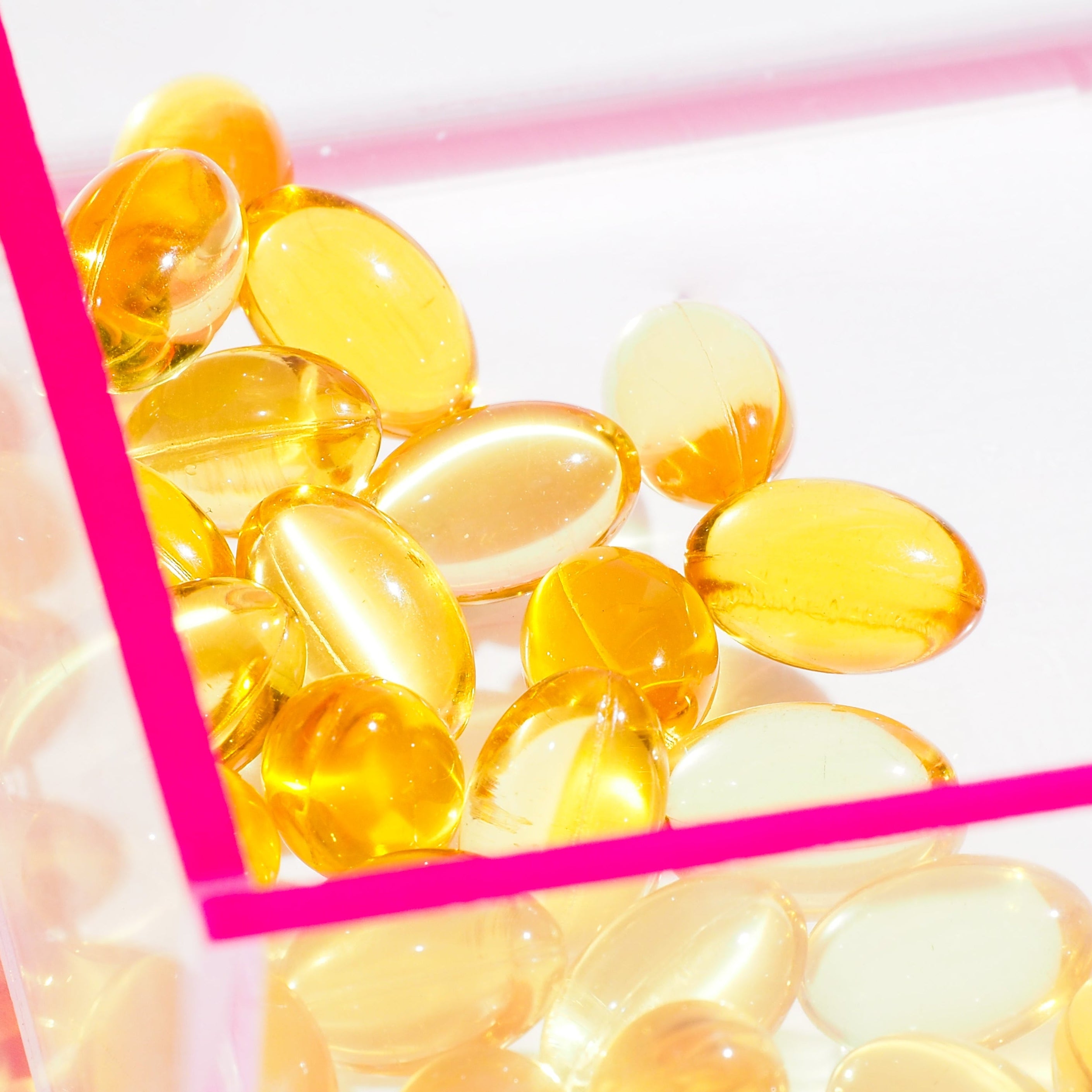 Yellow gel capsules on a white background with pink border