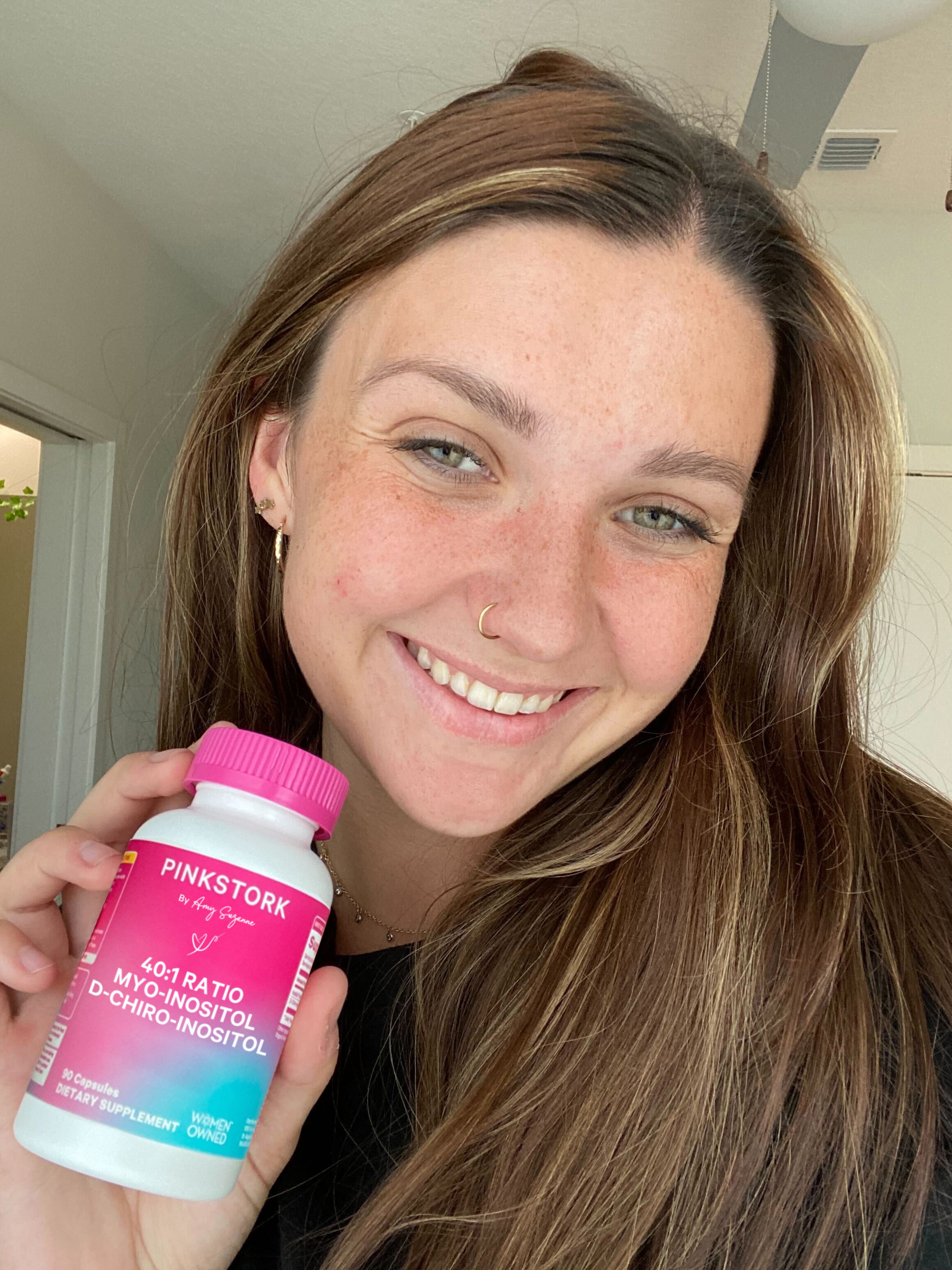 Person holding a Pink Stork supplement bottle with a pink cap