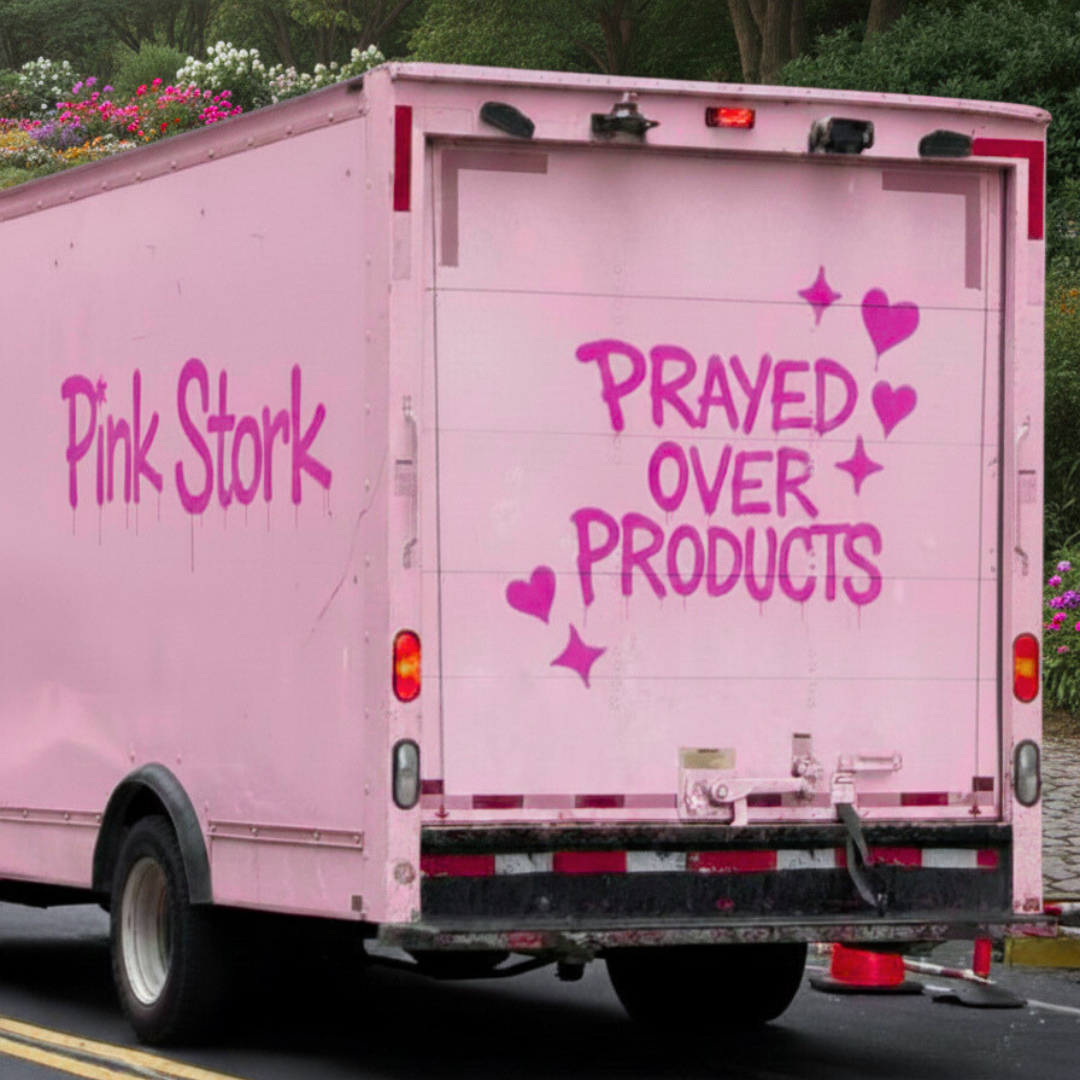 Pink truck with 'Pink Stork' and 'Prayed Over Products' text on a road.
