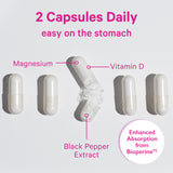 Five vitamin capsules all lined up with the middle one open and spilling out. Two capsules daily. Easy on the stomach. Magnesium, Vitamin D, and Black Pepper Extract.