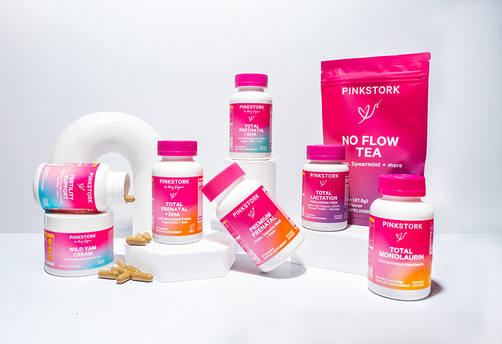 Group of Pink Stork products on white props and capsule spread out around them.