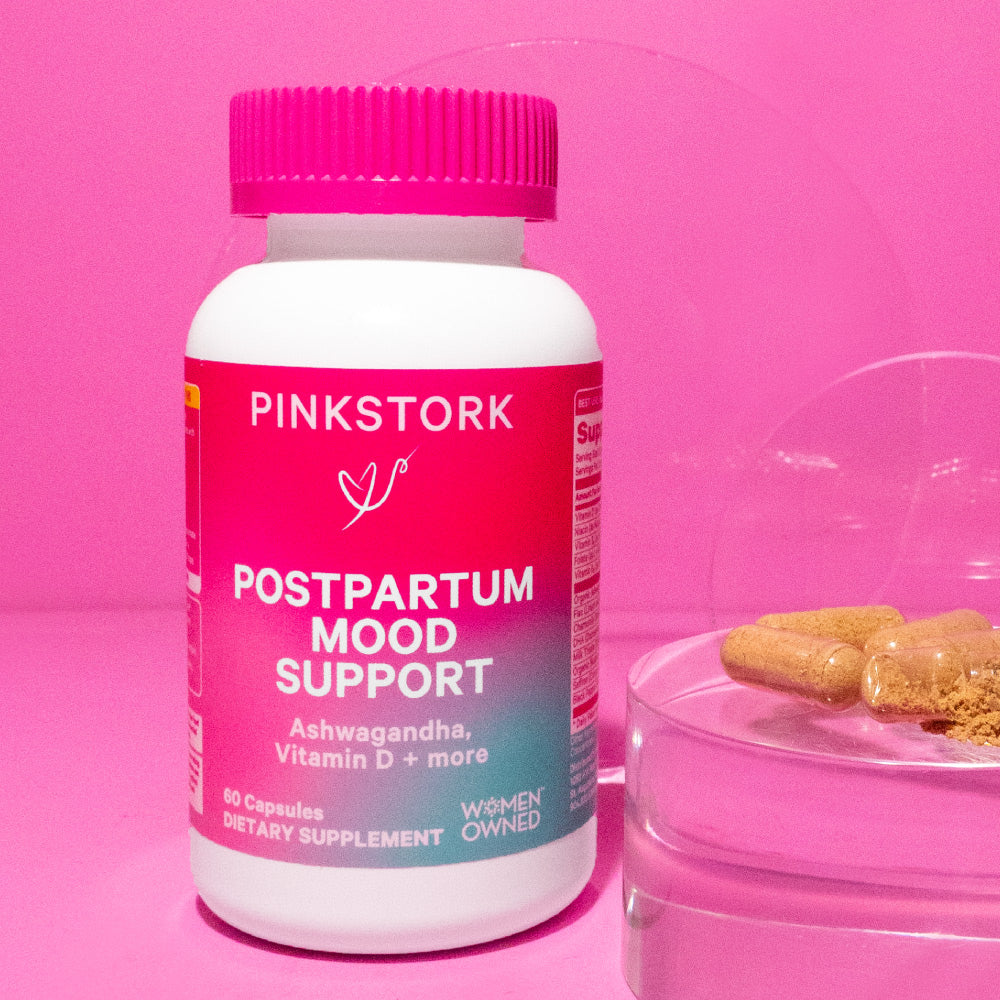 Bottle of Pink Stork Postpartum Mood Support with capsules next to it on a clear prism.