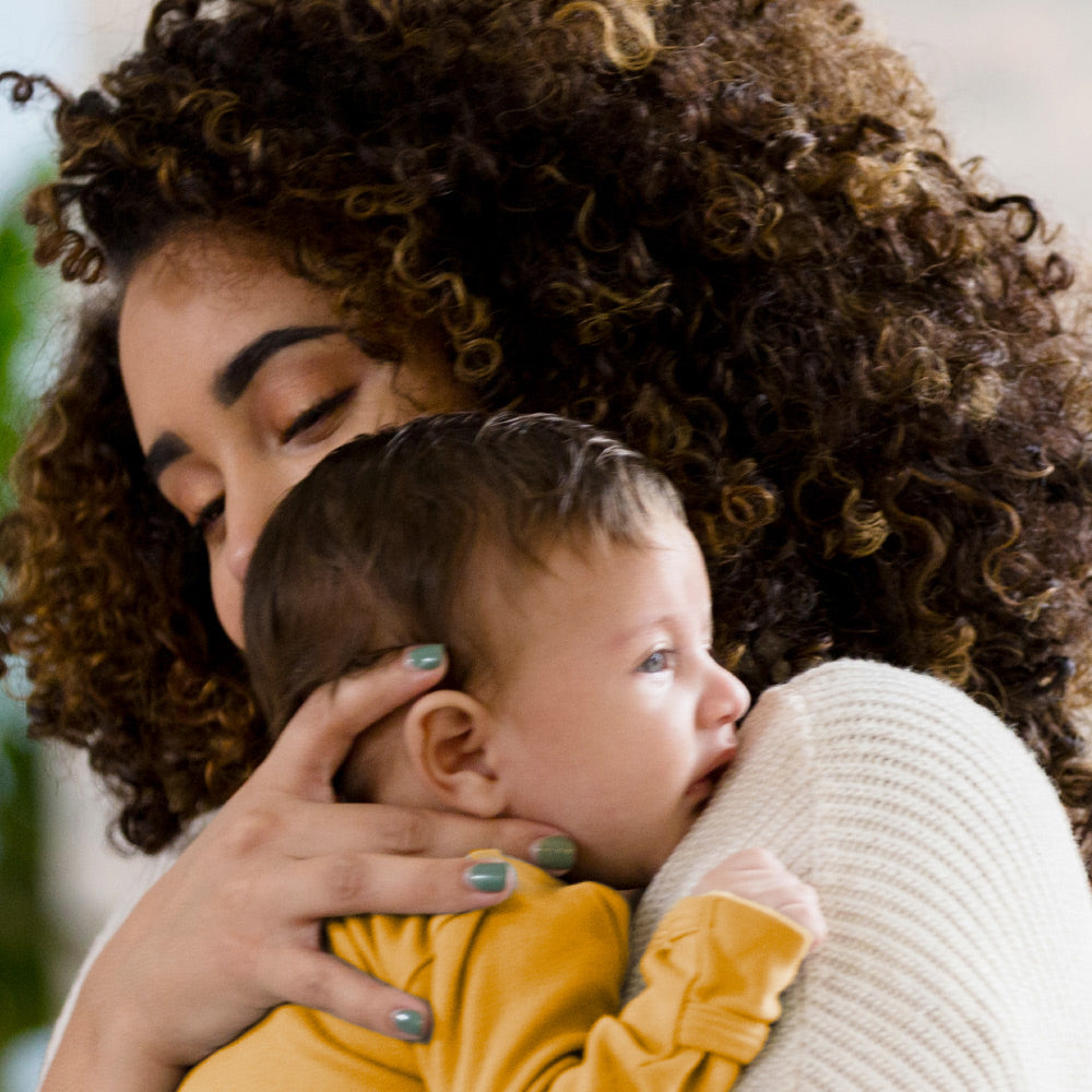 African American woman holding her baby up to her shoulder.