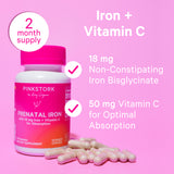 Pink Stork Prenatal Iron bottle with pile of capsules next to it. Iron + Vitamin C. 2 Month Supply.